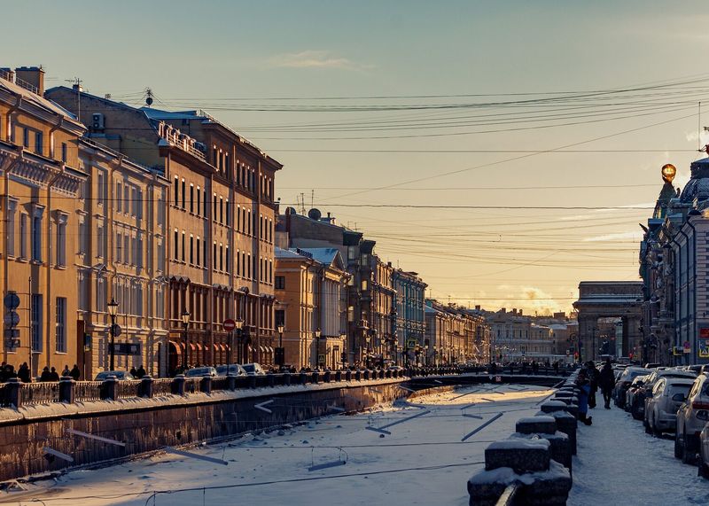 A frozen canal lined with pastel townhouses in winter, St Petersburg.